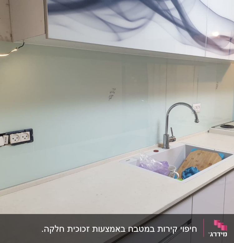 זכוכית שקופה על קיר מטבח מעל כיור וברז